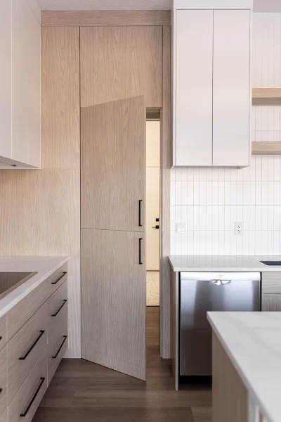 Hidden pantry door built flush into floor-to-ceiling natural wood cabinets