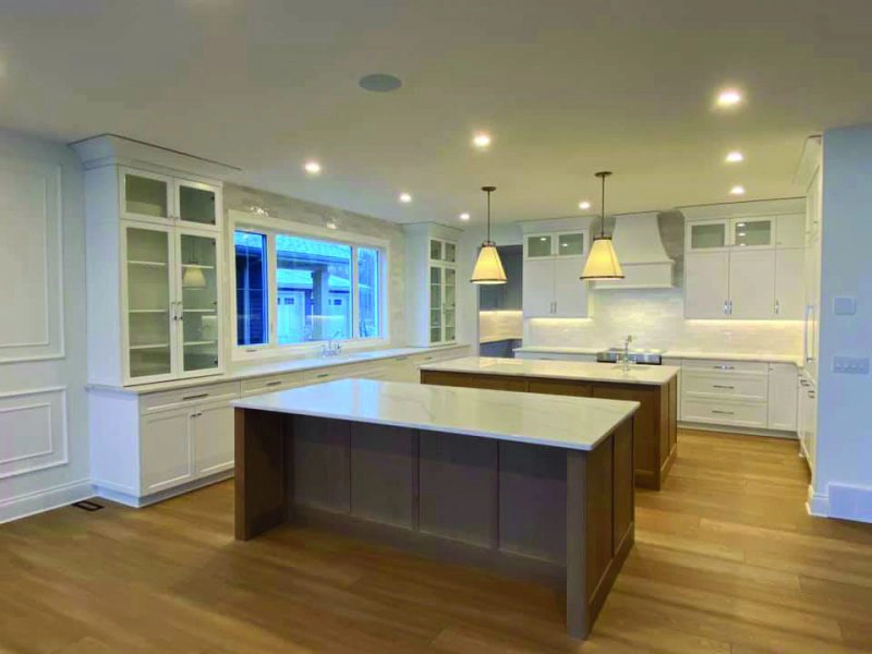 Large white kitchen with a double island and cabinets to the ceiling in a Sherwood Park home