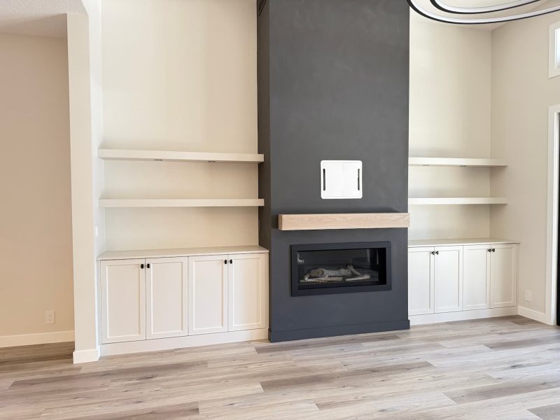 Fireplace wall with built-in cabinets and open shelves either side