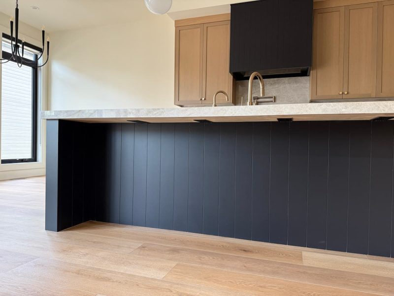 Two-tone kitchen with a black island and a custom hood fan in a Sherwood Park home