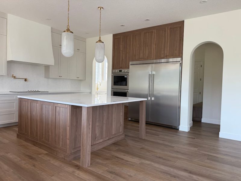 Two-tone custom kitchen with a wood-grain island, white uppers and a custom hood fan in an Ardrossan home