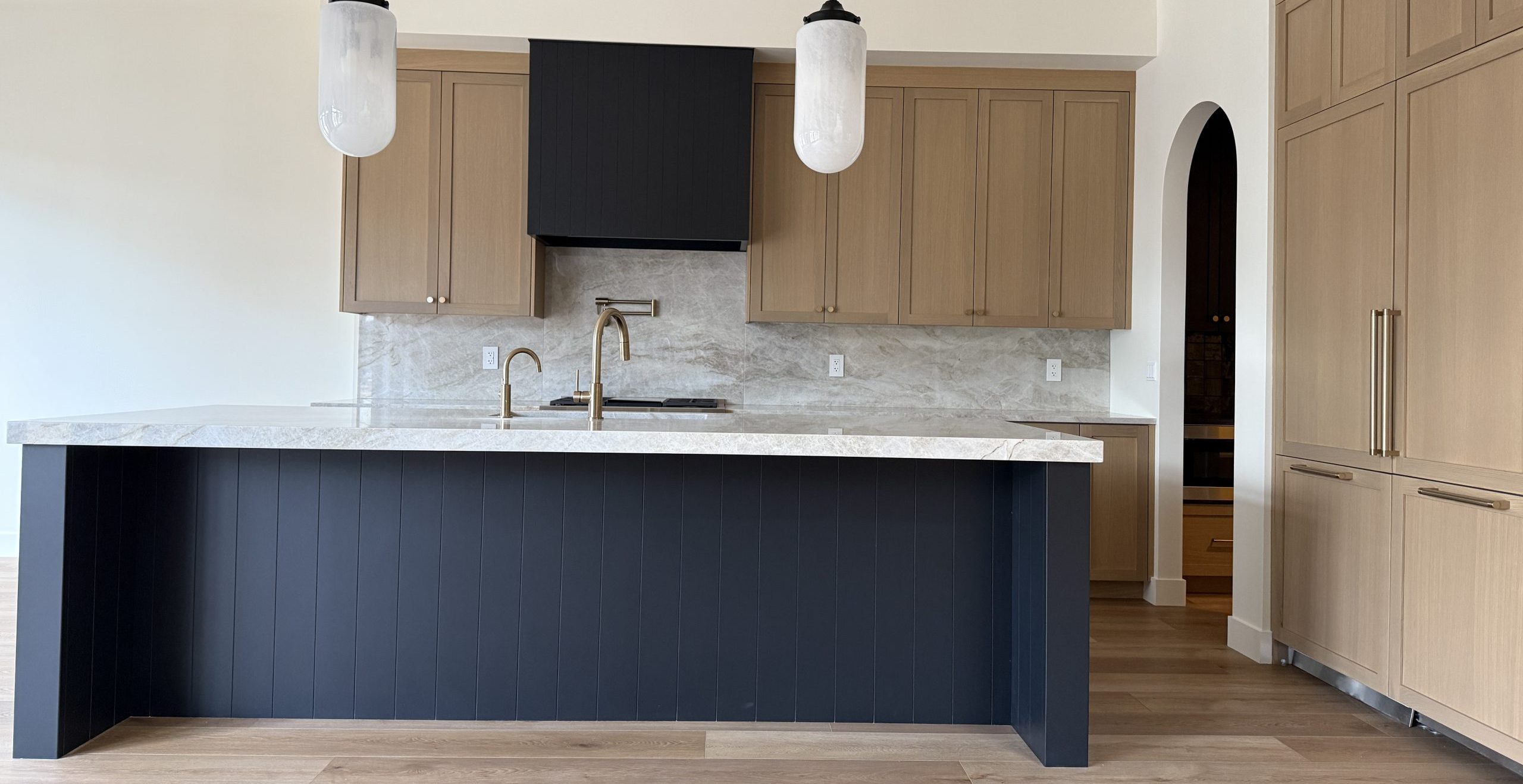 Two-tone kitchen with natural wood cabinets and a dark island in a Launch Homes build in Sherwood Park
